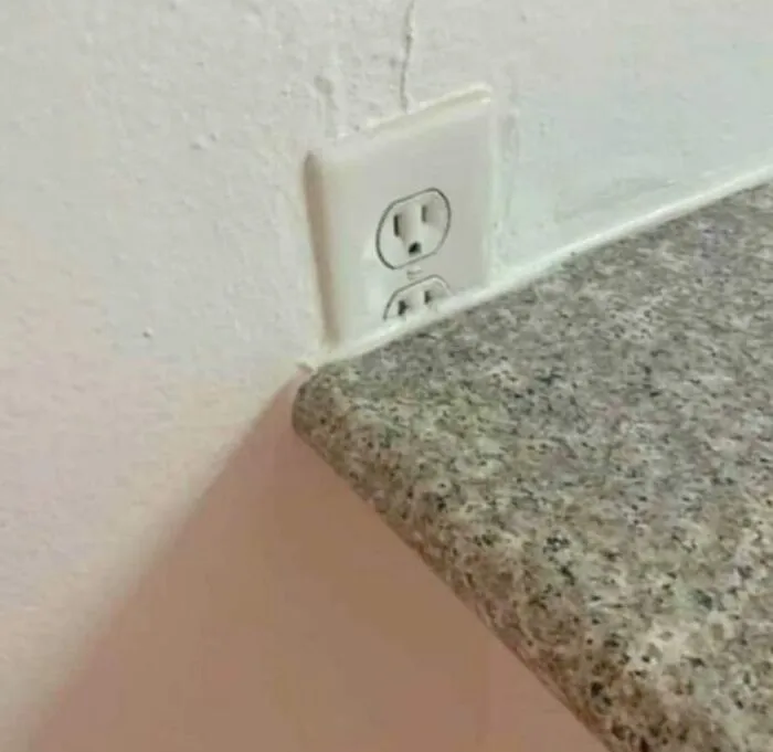 Electrical outlet partially blocked by countertop, illustrating a common engineering mishap.