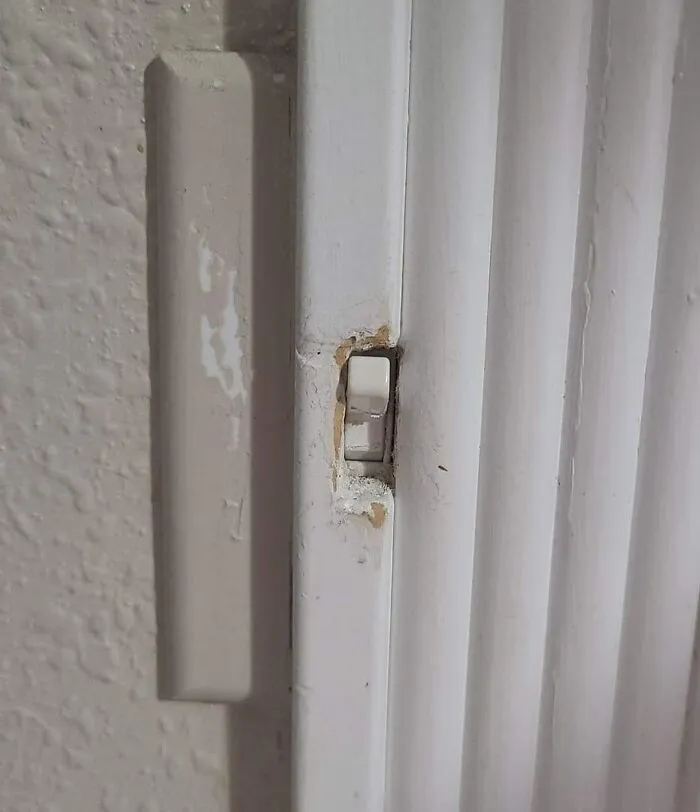 Light switch awkwardly installed on the edge of a door frame, showing a questionable engineering decision.