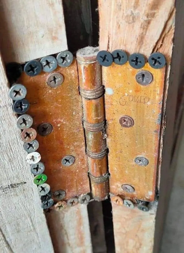 Door hinge poorly secured with mismatched screws, highlighting not all engineers exhibit smart solutions.
