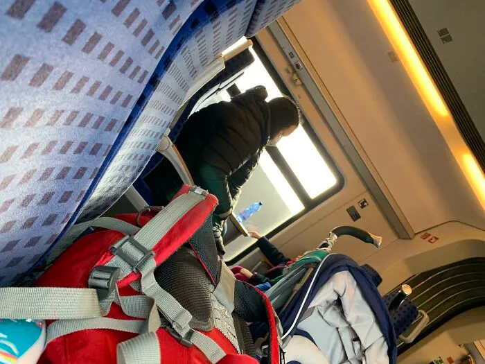 Passenger occupying multiple seats with a backpack on public transport.