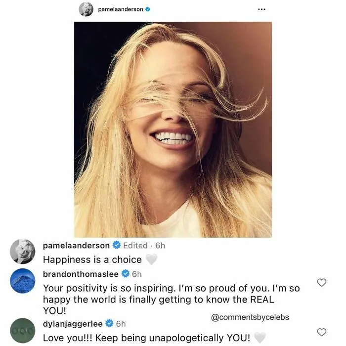 Smiling celeb with wind-swept hair shares inspirational comments, showcasing positivity and self-acceptance.
