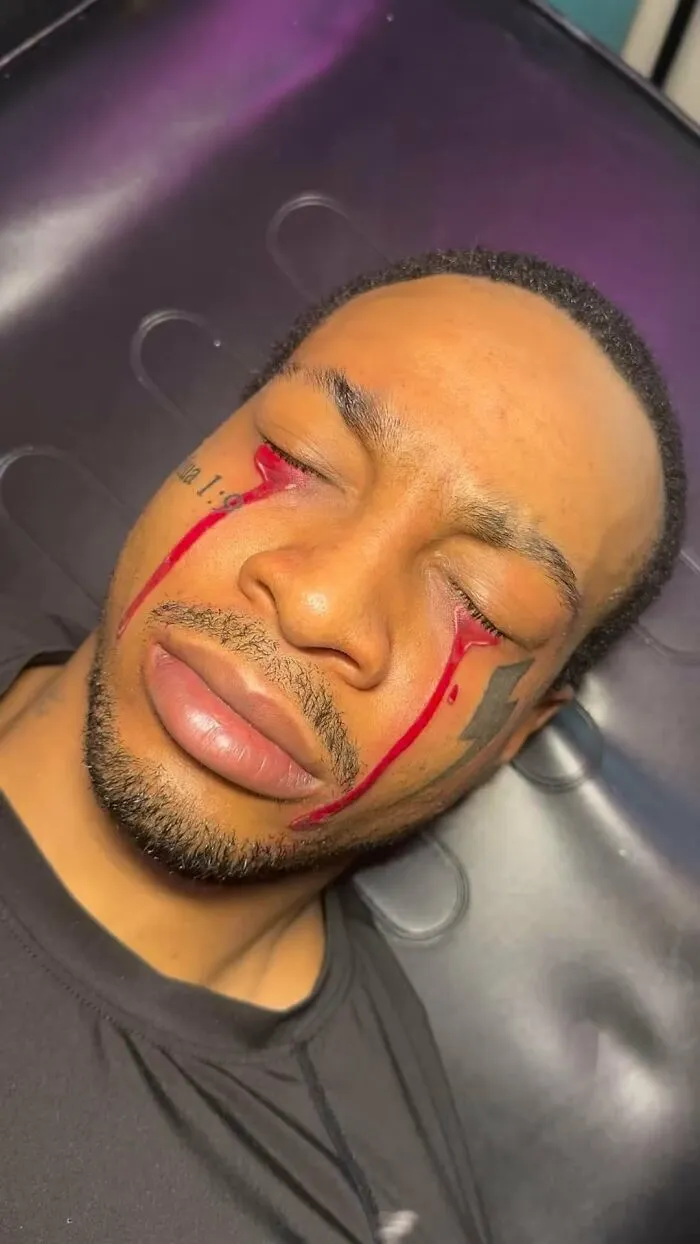 Man with face tattoos featuring red streaks, representing tattoo fails shared online.