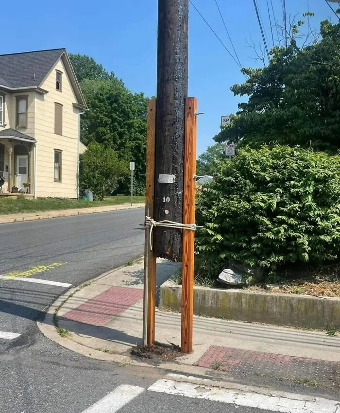 Utility pole with wooden support tied with rope, highlighting questionable engineering.