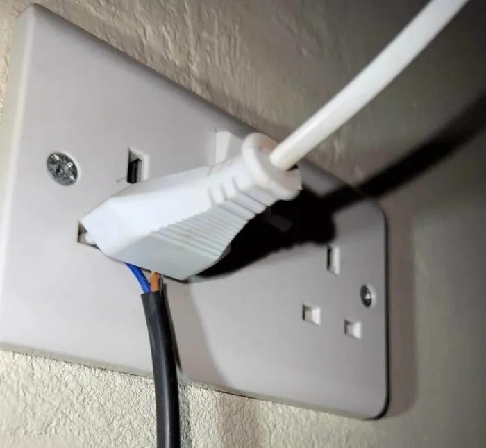 Electrical plug awkwardly inserted into outlet, illustrating a humorous engineering mistake.