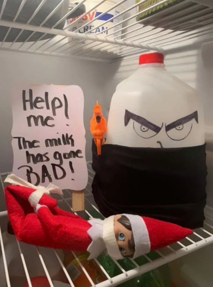 Elf On The Shelf idea with an elf tied up in fridge next to a menacing milk jug and a sign about bad milk.