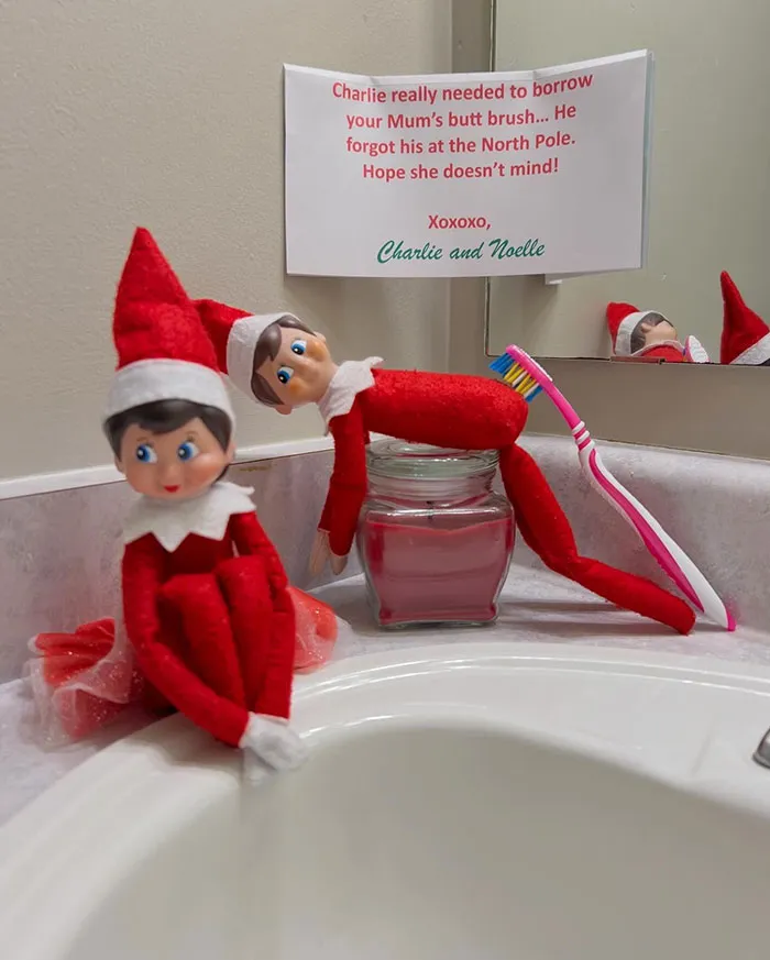 Two Elf On The Shelf dolls on bathroom counter with toothbrush and funny apology note for borrowing it