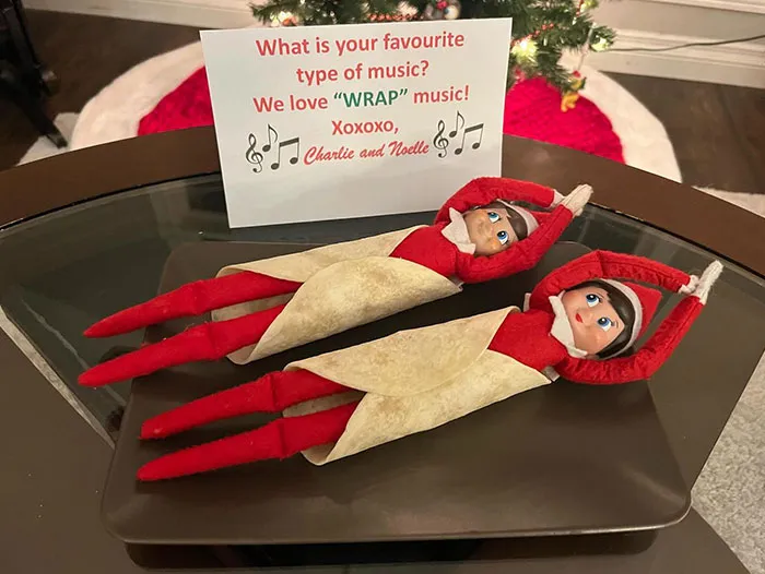 Two Elf On The Shelf dolls wrapped in tortillas on a tray with a note about loving wrap music, creative mischief idea.