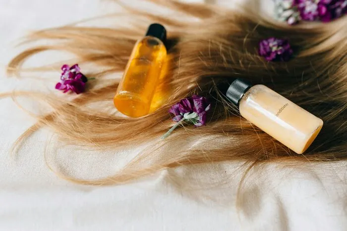 Bottles of scented oils on hair with purple flowers, symbolizing smell and happiness.