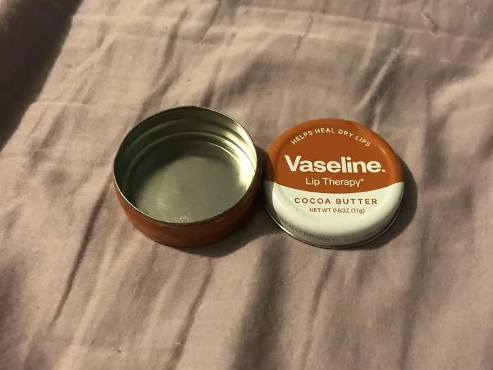 Open Vaseline cocoa butter tin, showing empty container on a soft fabric surface.