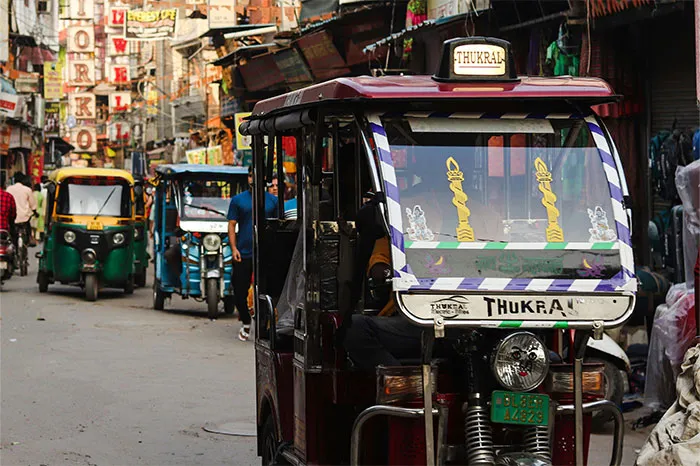 Bustling street with tuk-tuks in a popular travel destination, featuring vibrant signage and local shops.