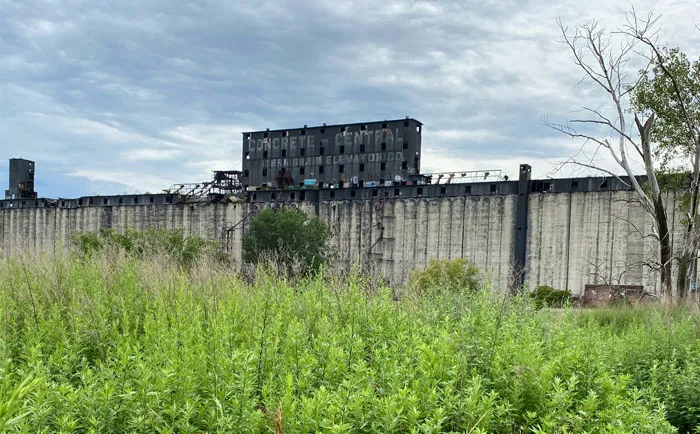Abandoned building in overgrown field under cloudy sky, representing disappointing travel destinations.