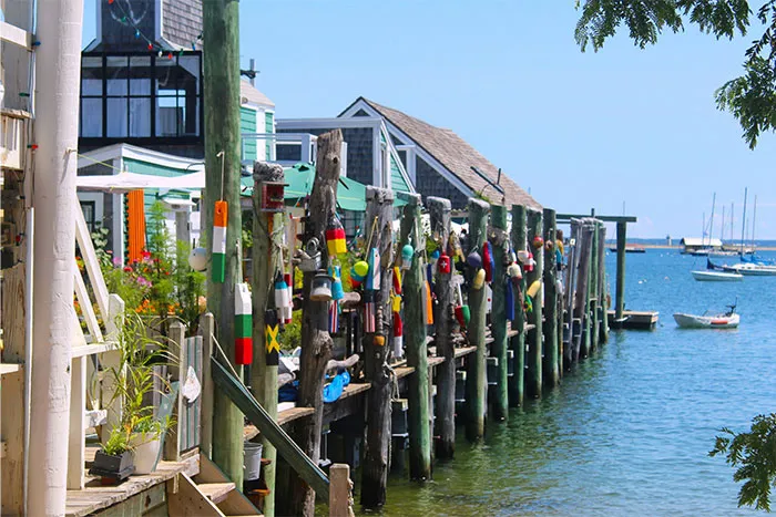 Colorful dock area by the water, featuring wooden posts adorned with vibrant buoys in a popular travel destination.
