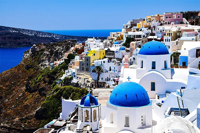 Blue-domed buildings in Santorini, a hyped travel destination, overlooking the sea.