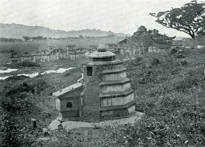 Ancient stone building with layered structure surrounded by overgrown vegetation, evoking supervillain headquarters aura.