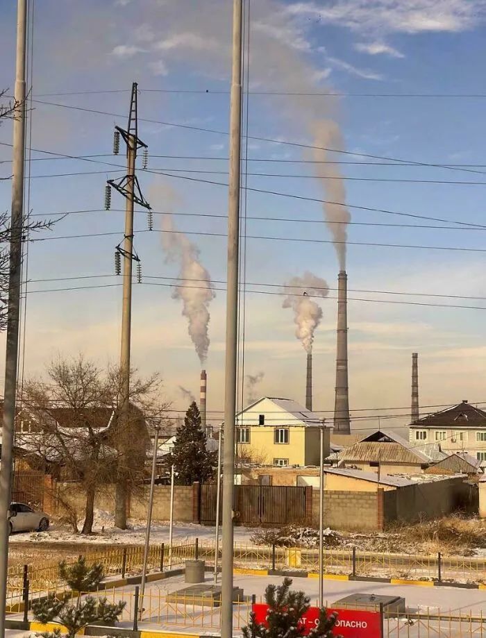 Chimeneas industriales emitiendo humo sobre un área residencial, representando un infierno urbano moderno.