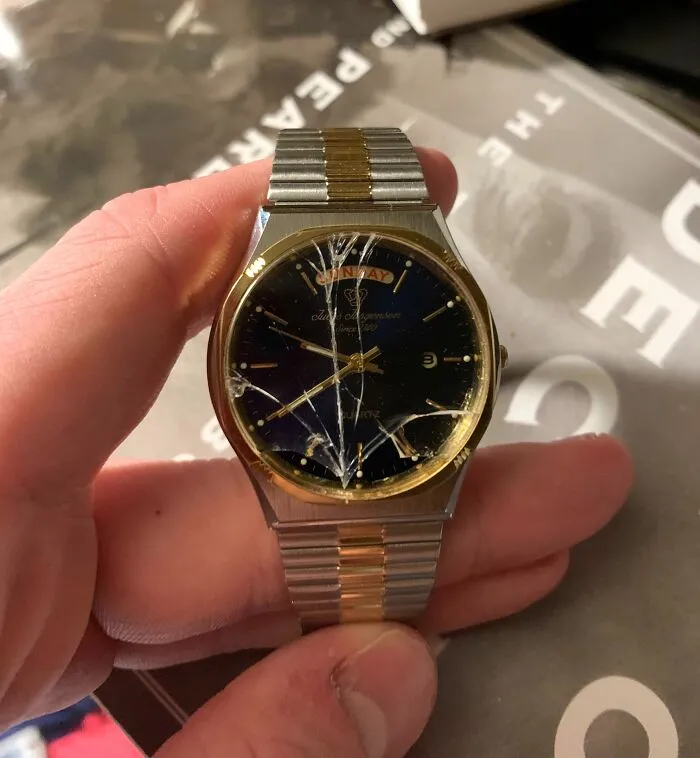 Cracked gold and silver watch face held in hand, symbolizing disappointing gifts.