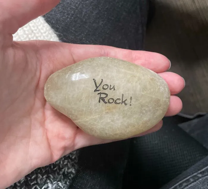 Hand holding a rock with "You Rock!" text, symbolizing disappointing presents.
