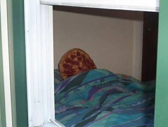 Cursed image of a pizza slice laying in bed, viewed through a window.