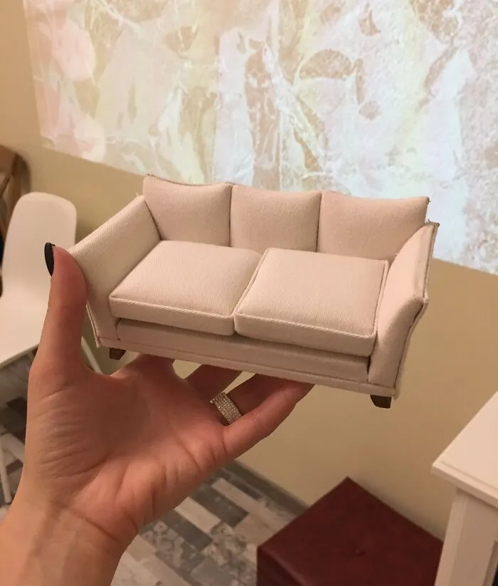 Person holding a miniature white sofa, illustrating a good-funny-bosses moment.