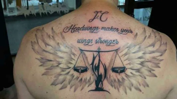 Back tattoo fail with misspelled quote, scales, and wings.