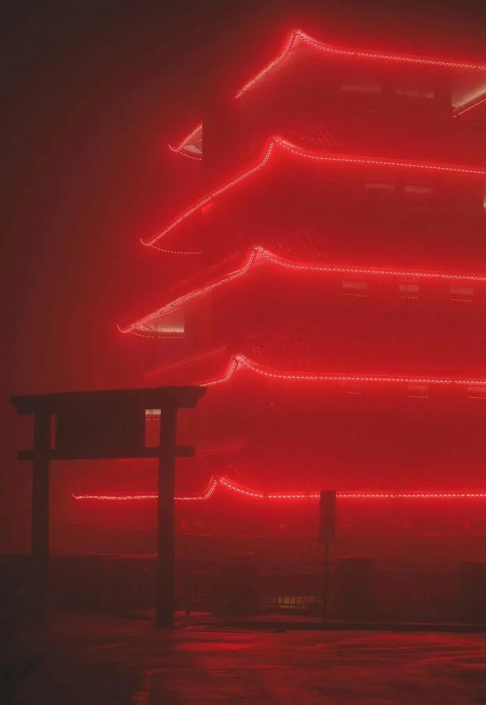 A multi-tiered building outlined in red lights shrouded in mist, exuding an evil aura like a supervillain headquarters.