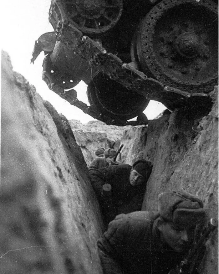 Soldados soviéticos agazapados en una trinchera al paso de un tanque ruso T-34 durante la batalla de Kursk, 1943