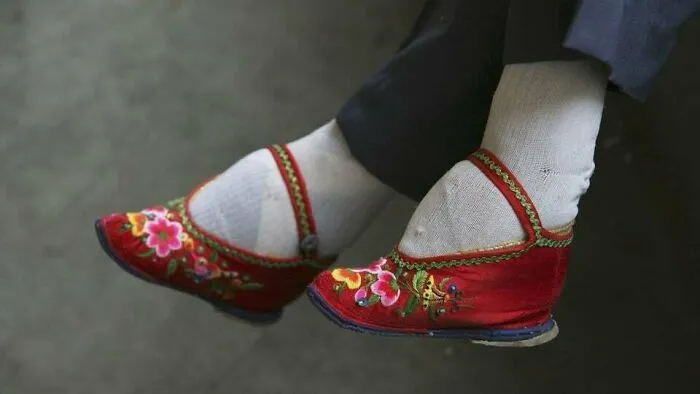 Feet in traditional red embroidered shoes with white socks, creating an oddly terrifying visual.