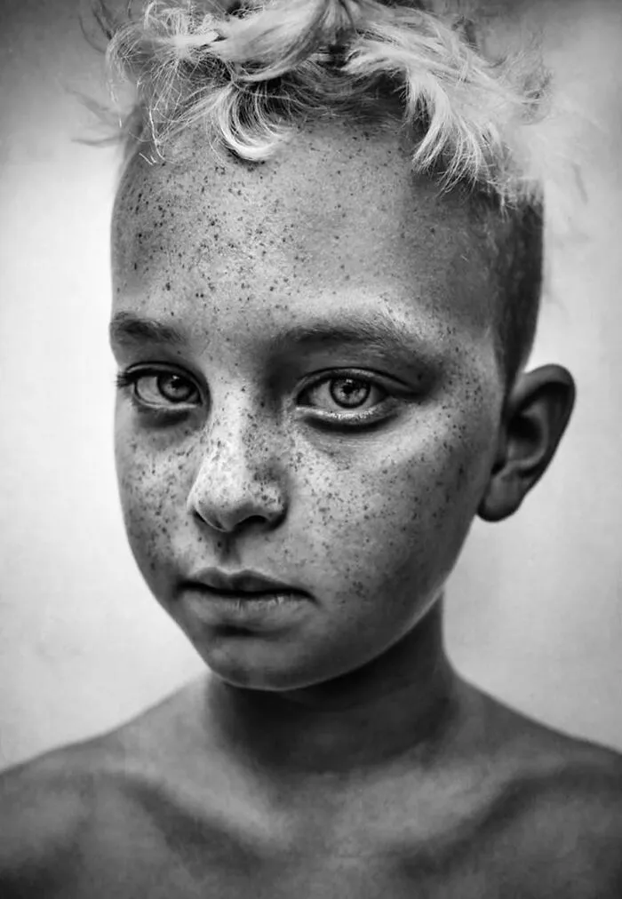 Freckled child portrait by Lee Jeffries, showcasing soulful expression.