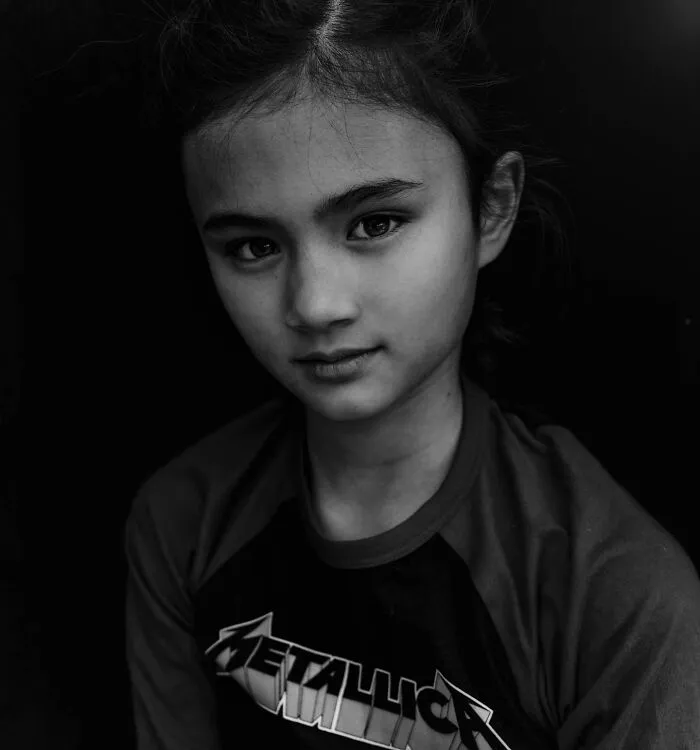 Black and white portrait of a young girl in a Metallica shirt by Lee Jeffries, focusing on soulful expressions.