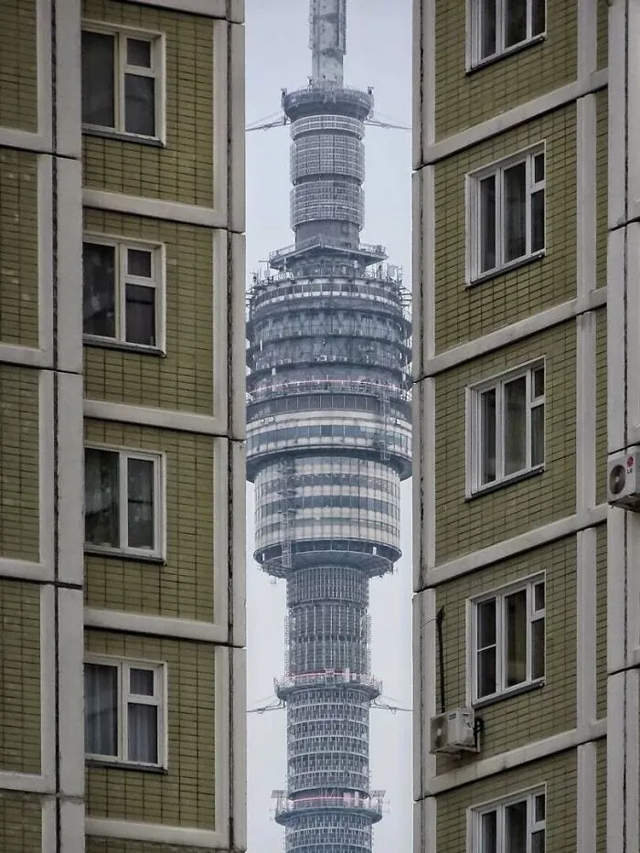 Torre urbana vista entre edificios, ejemplo de infierno urbano moderno.