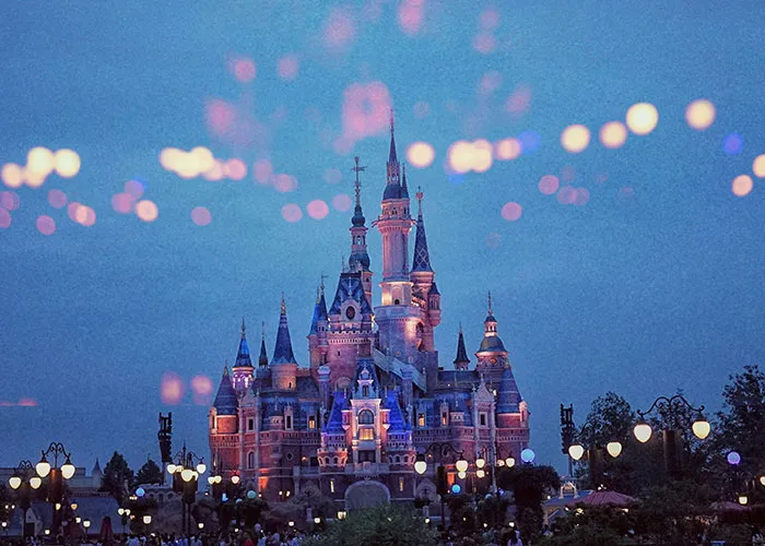 A beautifully lit castle at night, reflecting an enchanting atmosphere with blurred lights in the sky.
