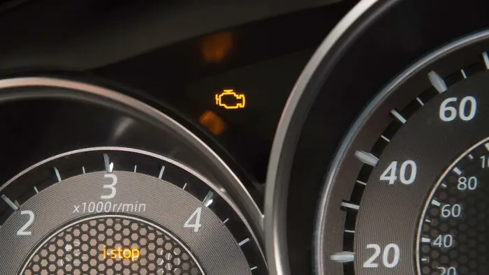 Car dashboard with check engine light on, indicating a common habit developed due to financial constraints.