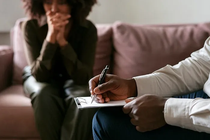 Person taking notes during a therapy session, reflecting on things adults buy after a denied childhood.