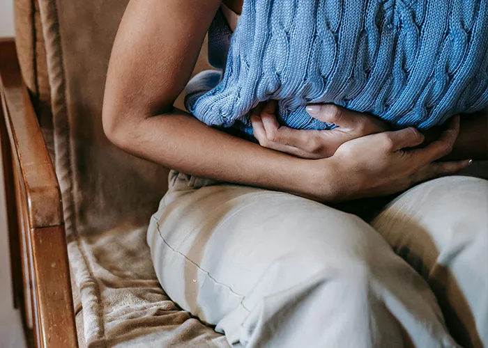 Person sitting uncomfortably, clutching their stomach, illustrating stress or discomfort during Christmas.