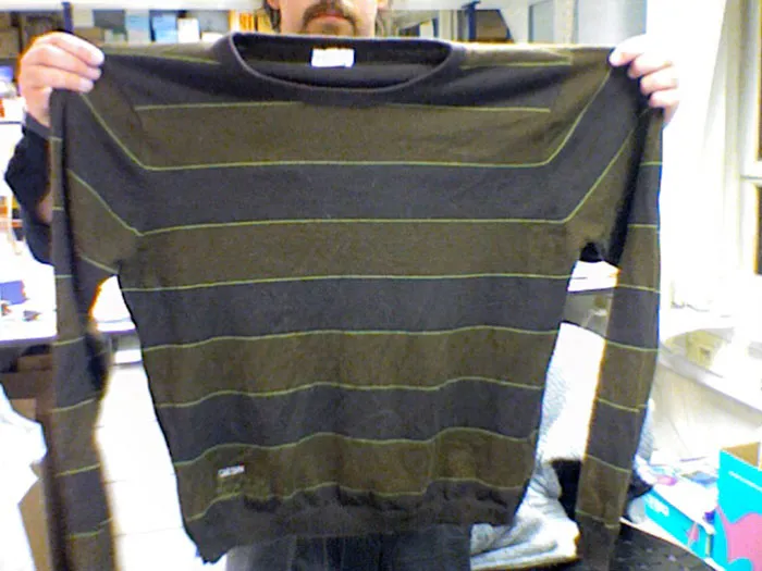 Person holding a striped sweater, one of many Christmas presents that ruined the holiday spirit.