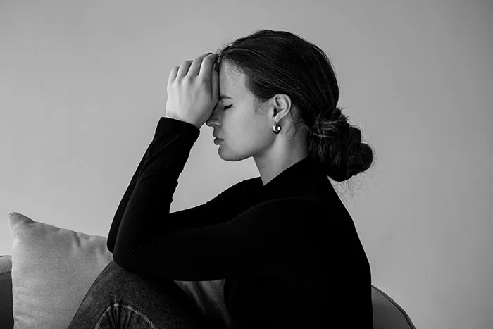 A woman sitting in frustration, illustrating ruined holiday spirit from unwanted Christmas presents.