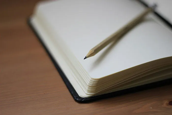 Open notebook with pencil on wooden desk, related to Secret Santa event mishaps.