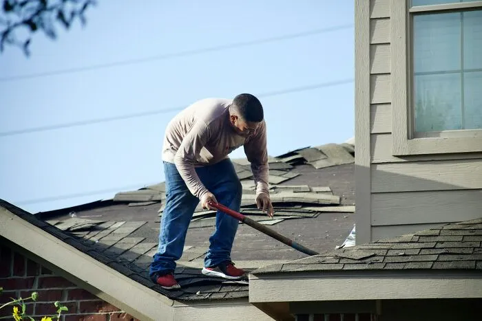 Person doing roof repairs, a common habit developed due to poverty, demonstrating resourcefulness and frugality.
