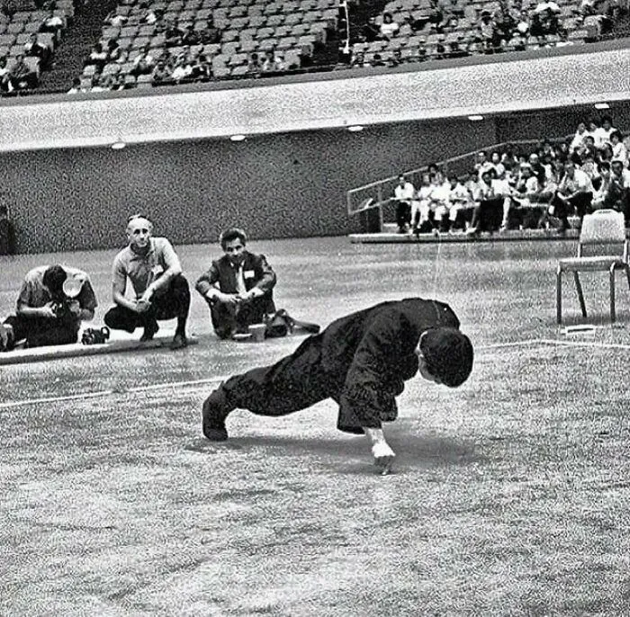Bruce Lee en un ejercicio de flexiones con dos dedos y un brazo, años 70