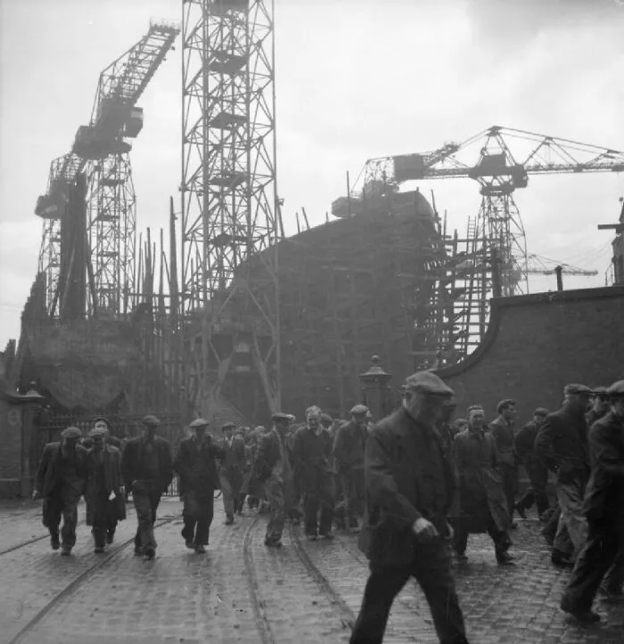 Workers Heading Out Through Gates Of A Shipyard For Lunchtime Break