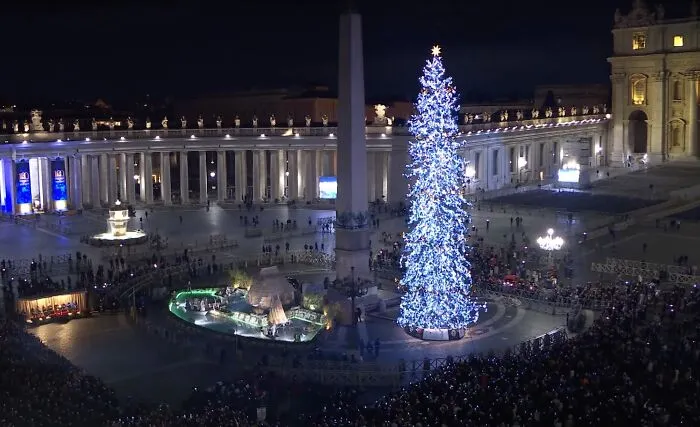 A luminous Christmas tree illuminated in a grand plaza, representing global holiday celebrations.