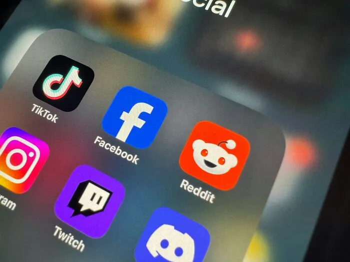 Social media app icons on a smartphone screen, including TikTok, Facebook, and Reddit, related to secrets and loved ones.