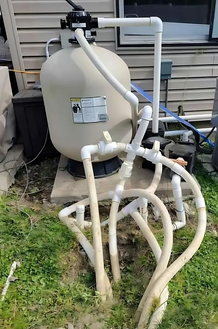 Bizarre construction plumbing setup with tangled pipes near a building wall, showcasing a construction fail.