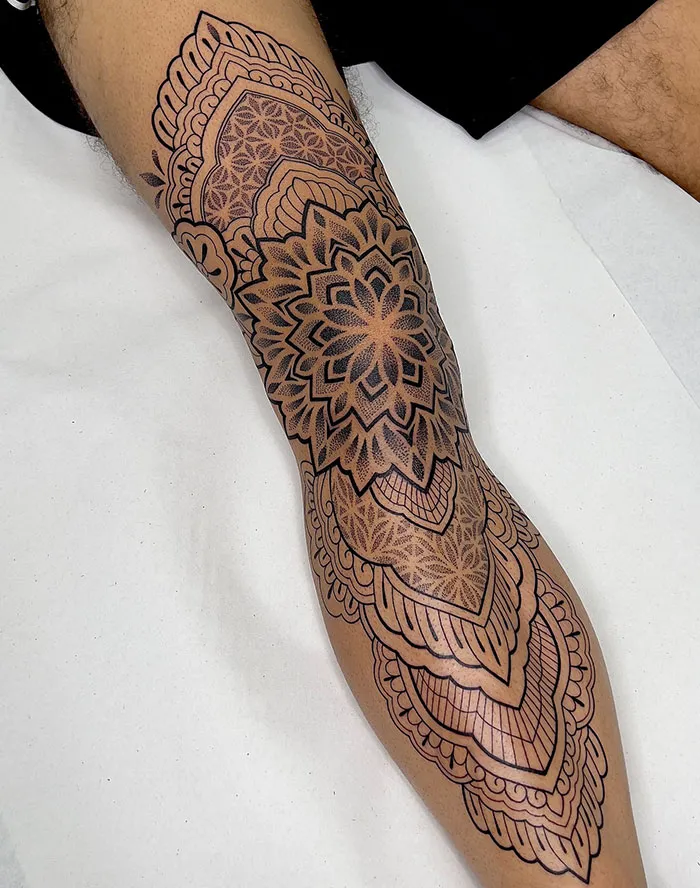 Intricate mandala tattoo design on a leg, showcasing detailed patterns and symmetry.