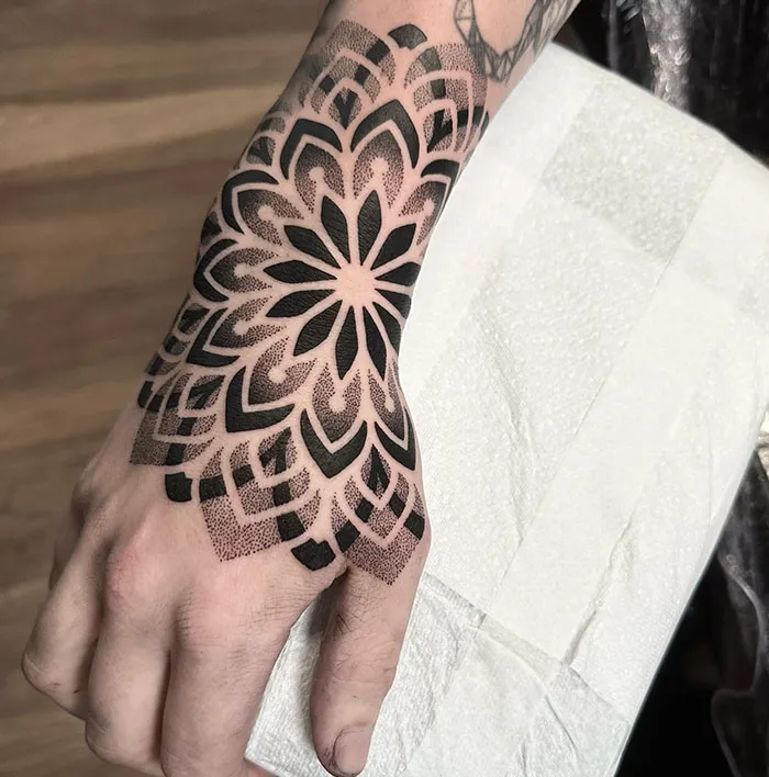 Mandala tattoo design on a hand, showcasing intricate black geometric patterns for meaningful body art.
