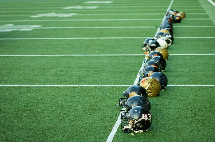 Football helmets lined up on a field, symbolizing future view of sports as possibly barbaric.