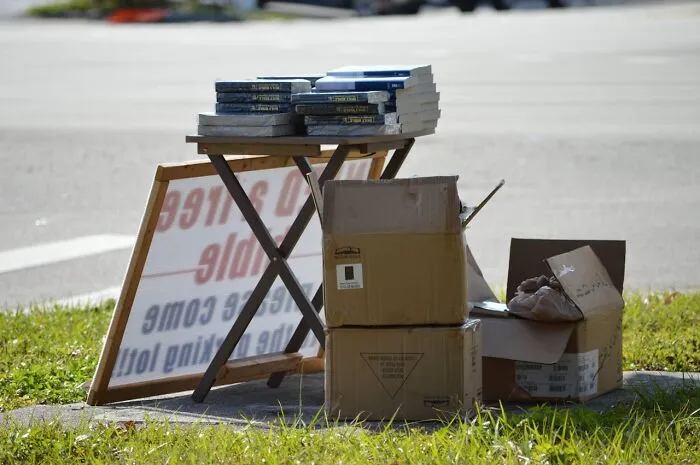 Outdoor book stand with cardboard boxes on grass, illustrating a frugal habit developed due to poverty.