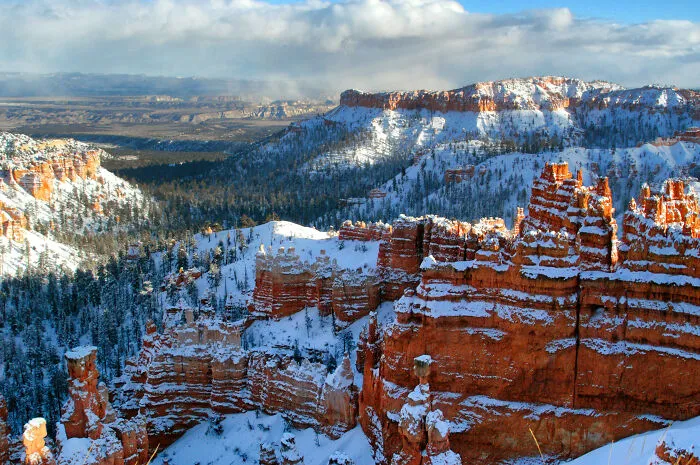 Snow-covered canyons and rock formations under a vast sky, showcasing amazing views and natural beauty.