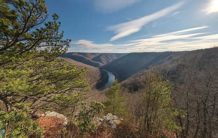 Scenic view of a winding river through lush green hills under a clear blue sky, showcasing amazing views in nature.