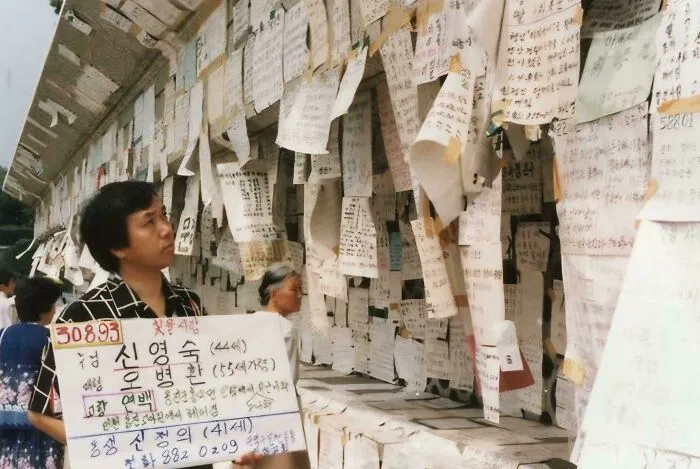 Man Looking At Other Posters Looking For Missing Families With One Of His Own